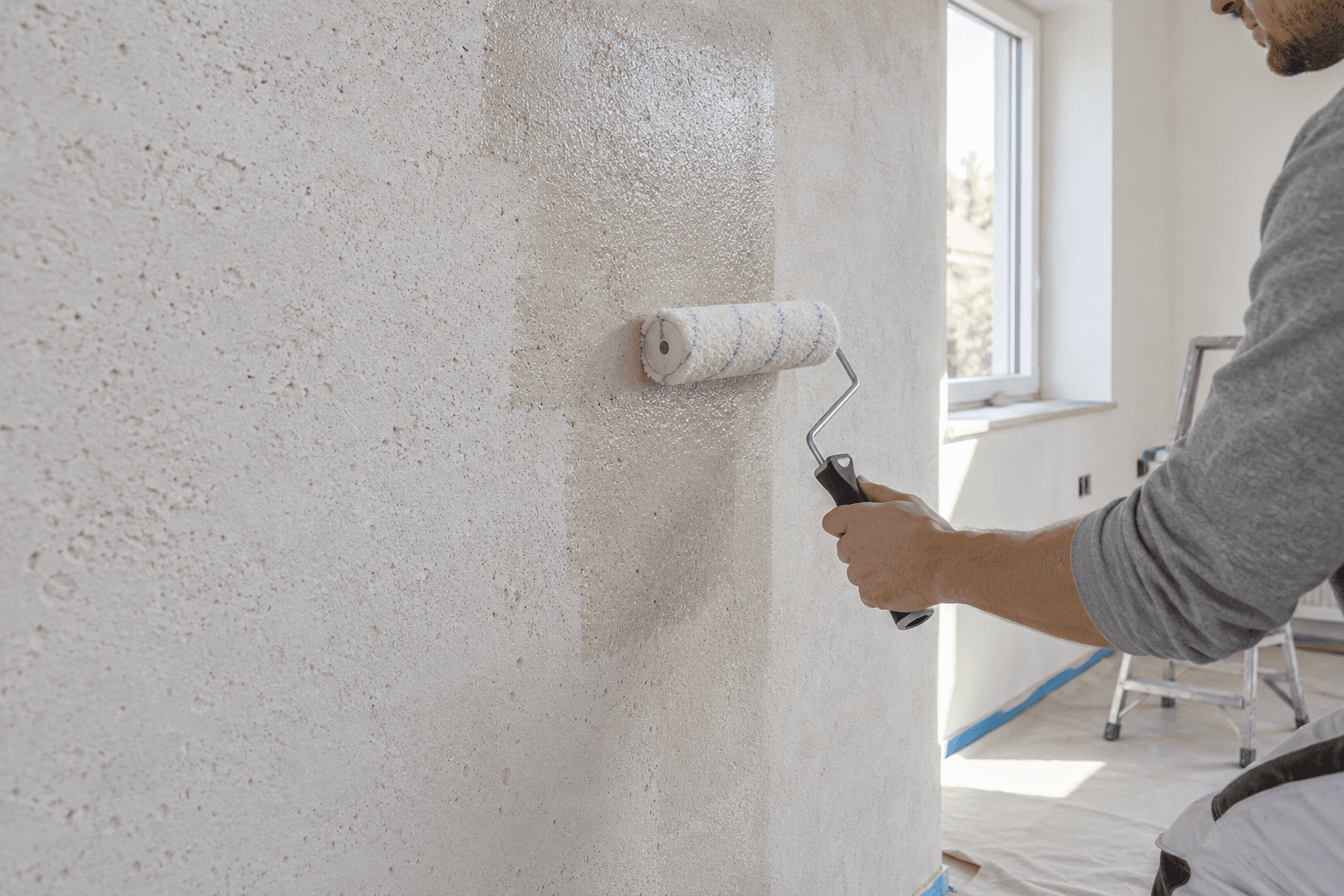 Contractor rolling clear wall sealer onto a porous mineral wall
